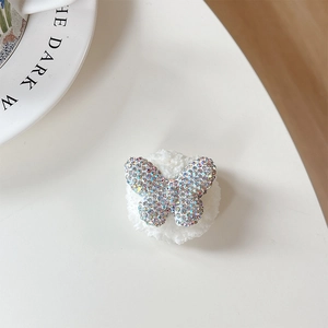 Detail of plush bear phone socket featuring a butterfly rhinestone bow and luxury finish
