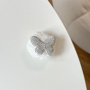 Detail of rhinestone butterfly phone grip with silver metal frame and white plush ball base