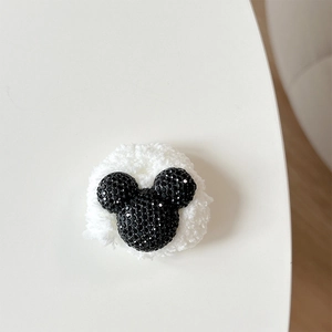 Detailed close-up of plush white fleece scrunchie with sparkling black rhinestone bear head