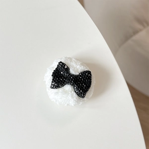 Detail of plush bear phone socket featuring a black rhinestone bowknot on white faux fur