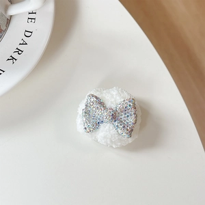 Macro detail of plush white teddy bear phone socket with sparkling rhinestone bowtie