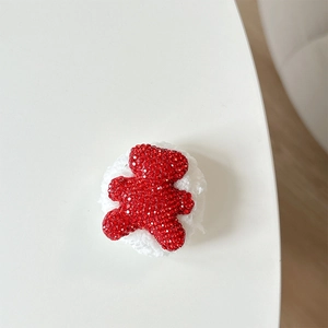 Detail of red rhinestone bear phone grip with white plush backing on a white surface