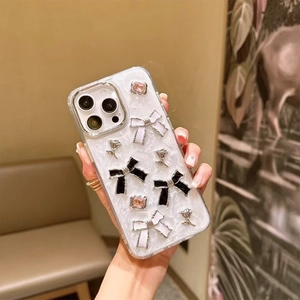 Detail of white shell texture phone case with 3D bows and rhinestones held by hand