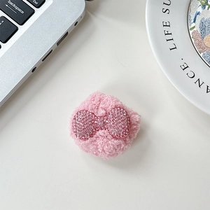 Close-up of plush pink phone socket with rhinestone bow detail on a stylish desk