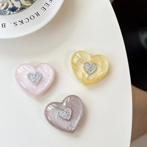 Detailed view of 3D heart-shaped phone grips in pink, yellow and purple with glitter finish