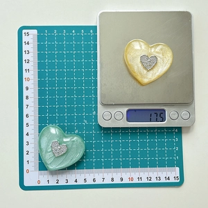 Macro view of heart-shaped resin phone grips in light yellow and green with pearly finish