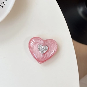 Detail of pink pearlescent heart phone grip with silver logo and glossy resin finish