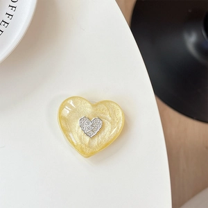 Detail of a 3D heart phone socket in pearlescent yellow with a silver textured heart