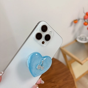 Close-up of glitter heart phone grip with cherry crystal on a white smartphone