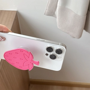 Detailed close-up of pink leather strawberry phone grip with premium stitching on phone