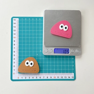Detail showing pink and brown leather triangle phone stands with eye patterns and size scale