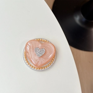 Makro-Detail des rosa Herz-Handyhalters mit Perlglitzer und Strass-Logo