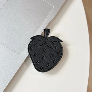 Macro shot of black leather strawberry phone grip featuring lychee texture and fine stitching