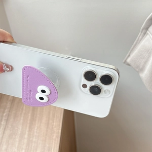 Close-up of purple leather phone grip with cartoon big eye design on a white phone