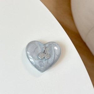Macro detail of heart-shaped phone grip with glitter marble texture and rhinestone cherry