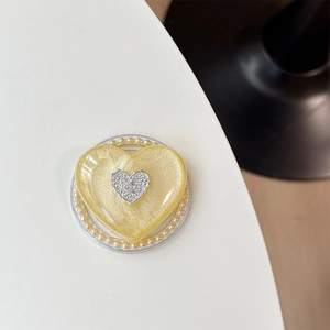 Makroansicht der herzförmigen MagSafe-Halterung mit gelbem Perleffekt und Goldperlenrand