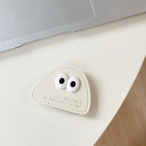 Macro detail of cream leather phone grip with cute eye decor and embossed quote