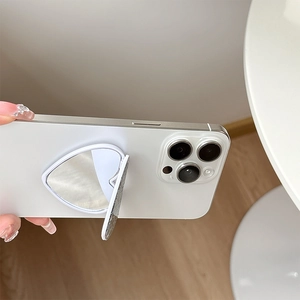 Close-up of a white heart-shaped folding phone stand mirror attached to a smartphone