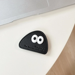 Close-up of black leather phone stand featuring cartoon eyes and mountain engraving