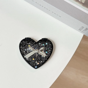 Macro shot of heart-shaped folding mirror with black sequins and a metal bow decoration
