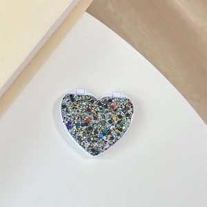 Close-up of heart-shaped folding makeup mirror with colorful glitter and white plastic frame