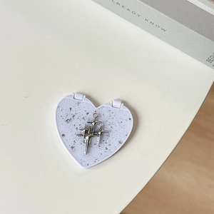 Macro detail of silver star-shaped pendant on glittery heart mirror accessory