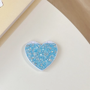 Detail of a heart-shaped makeup mirror with sparkling blue glitter and white frame