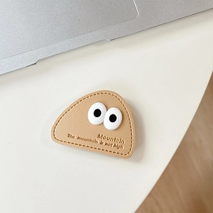 Detail view of khaki leather phone grip with mountain embossing and cute large 3D eyes decoration