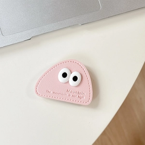 Detail of pink triangular leather phone grip with cartoon eyes on a white desk