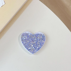 Close-up of heart-shaped phone grip with purple glitter and shimmering sand texture