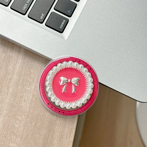 Détail du support téléphone rose avec nœud argenté et bordure perles sur bureau