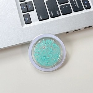 Macro shot of circular phone grip filled with light blue sequins on a desk surface