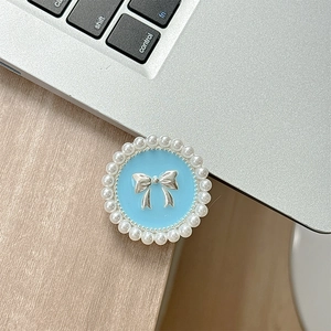 Détail du support téléphone en émail bleu avec nœud argenté et bordure perle