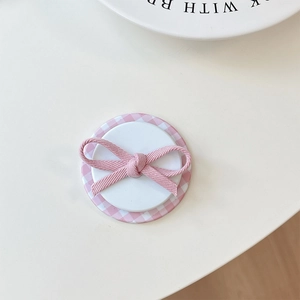Detail of pink plaid bow phone grip with soft ribbon texture on white background