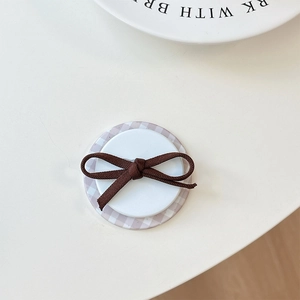 Close-up of a brown fabric bow on a purple checkered magnetic phone socket stand