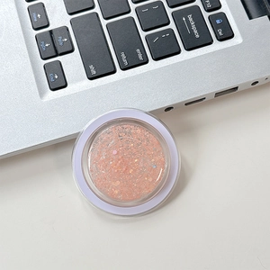 Close-up of glitter sequins for phone socket accessory in round peach orange container