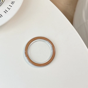 Detail of transparent MagSafe phone grip base with brown inner ring on white surface