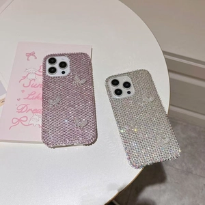 Sparkling pink and silver rhinestone iPhone case with 3D butterfly design on a table
