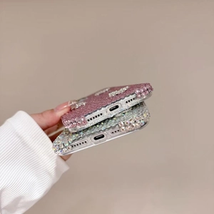 Detail showing high-density rhinestone inlay process on pink and silver luxury phone cases