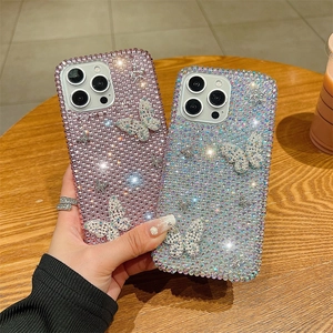 Coque iPhone 16 Pro Max ornée de strass brillants et de papillons 3D sur fond de bois