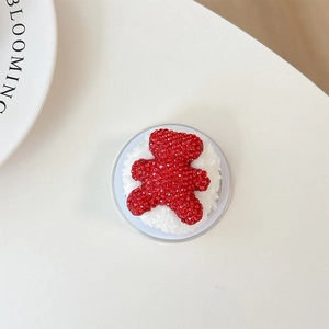 Detailed macro view of red rhinestone bear phone grip with soft white plush base