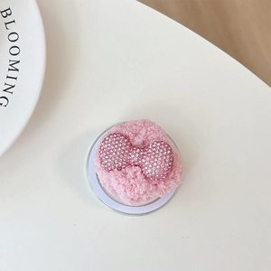 Close-up of pink plush phone grip with sparkling rhinestone butterfly bow detail