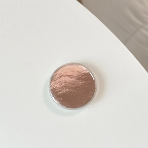 Macro shot of rose gold round phone socket with metallic crinkle texture on white background