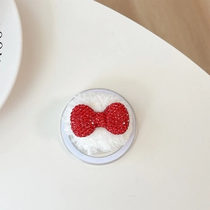 Detail of red rhinestone bow decoration on white plush phone grip base for women