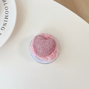 Detail of pink plush phone grip with sparkling rhinestone heart on a soft background