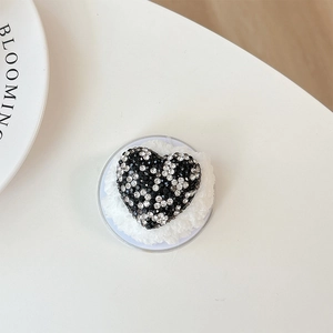 Detail shot of a heart-shaped luxury rhinestone accessory on soft white plush base