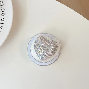 Detailed macro view of heart-shaped rhinestone phone grip with soft white plush padding