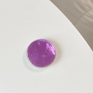 Close-up of circular purple metallic foil seal with reflective texture for phone grip