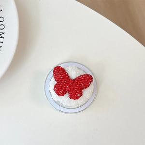 Macro shot of red rhinestone butterfly phone holder on soft white faux fur base