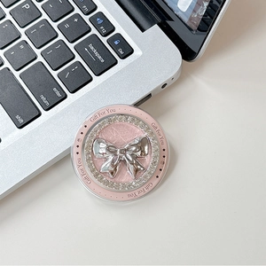 Pink MagSafe phone grip with silver bow and rhinestones on a laptop keyboard